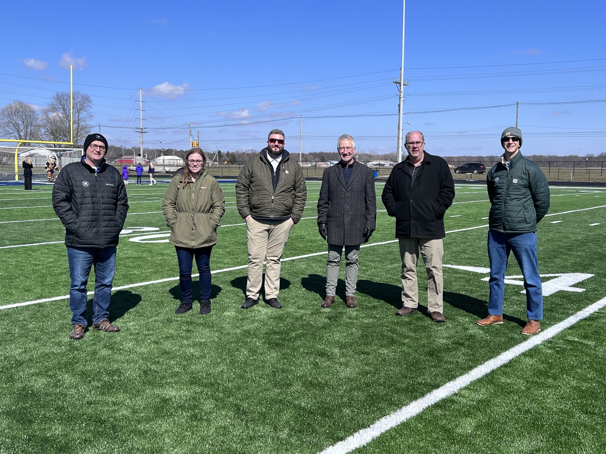 6 people standing on football field