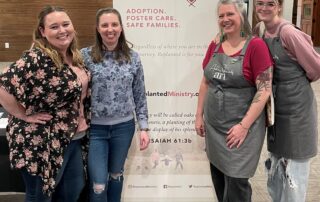 4 smiling women standing by banner
