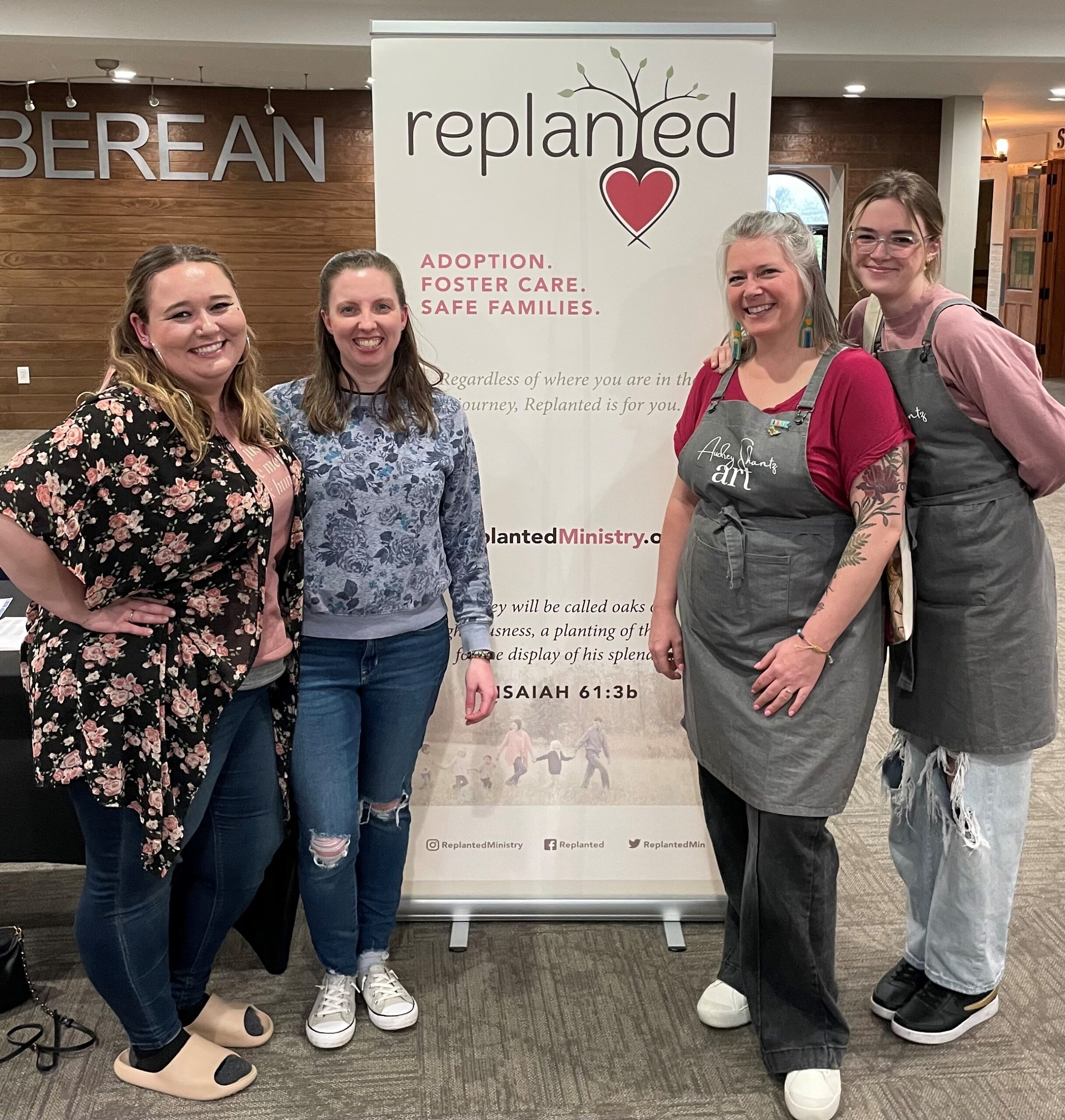 4 smiling women standing by banner